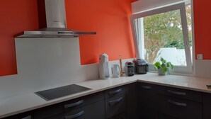 A modern kitchen with a white countertop, black cabinets, and a red accent wall.