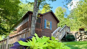 Eine Holzhütte mit einem Balkon und einer Treppe zu einer Terrasse.