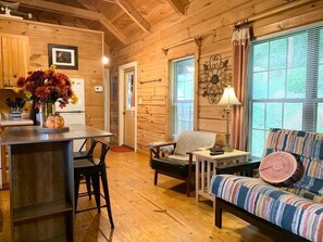 A cozy cabin interior with a wooden dining table, chairs, a sofa, and a window with blinds. - Autumn Splendor Cabin walk Chimney Rock/Lake Lure (Lake Lure)
