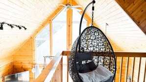 Un interior de madera con una silla colgante, un televisor y vistas al exterior.