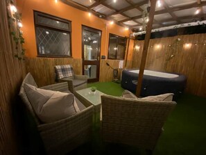 A cozy outdoor seating area with wicker furniture and a hot tub.