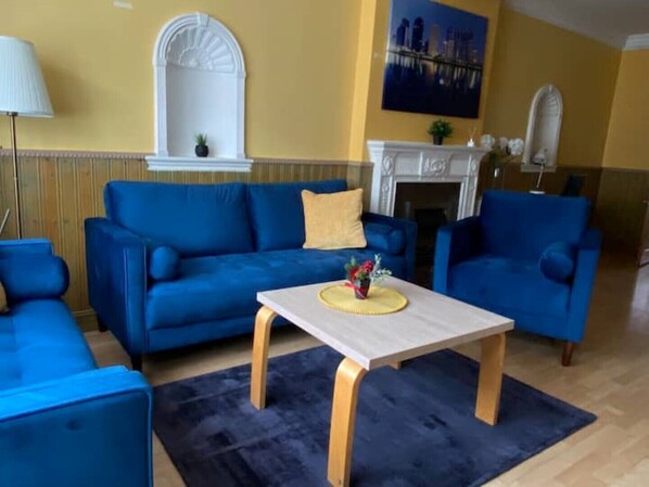 A living room with a blue sofa set, a wooden coffee table, and a fireplace.