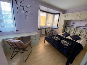 A bedroom with a bed, a desk, and a chair.