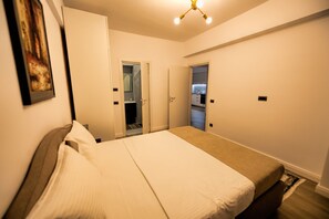 A bedroom with a bed, a wardrobe, and a door leading to a bathroom and kitchen.