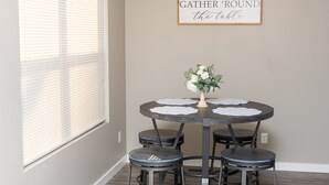 A dining area with a round table, four chairs, and a wall-mounted sign.