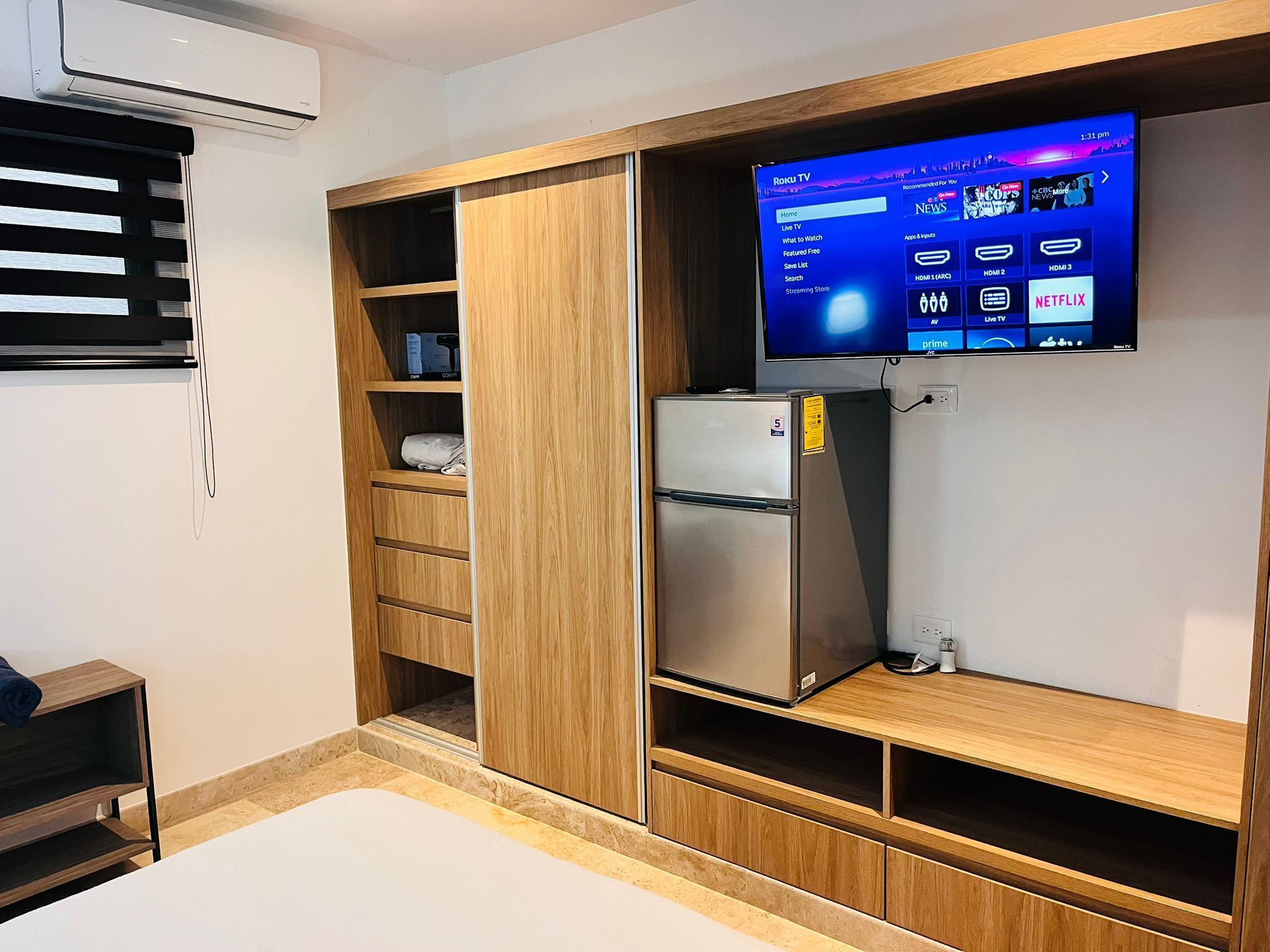 Ein gemütlicher Raum mit integriertem Fernseher, einem Kühlschrank und Holzregalen.