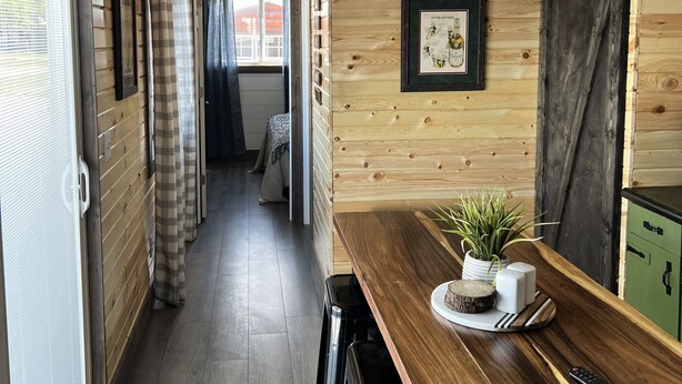 A wooden interior with a kitchen area, including a wooden table, chairs, and a green cabinet. - Sleeps 8 — Bunkhouse (Platte)