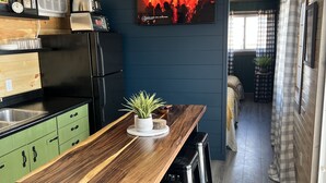 A modern kitchen with a wooden table, bar stools, and a TV mounted on the wall. - Sleeps 8 — Bunkhouse (Platte)