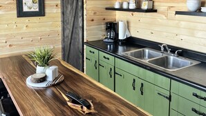A modern kitchen with wooden walls, green cabinets, and a wooden countertop. - Sleeps 8 — Bunkhouse (Platte)