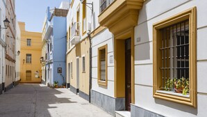 Uma rua estreita com edifícios que têm varandas e janelas com grades de metal.