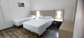 A room with two single beds and one double bed, wooden flooring, a desk, and a chair. - Italian Hotel (Parauapebas)