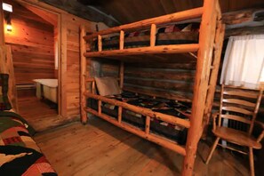 A rustic cabin interior with a wooden bunk bed, a small wooden chair, and a wooden door leading to another room.