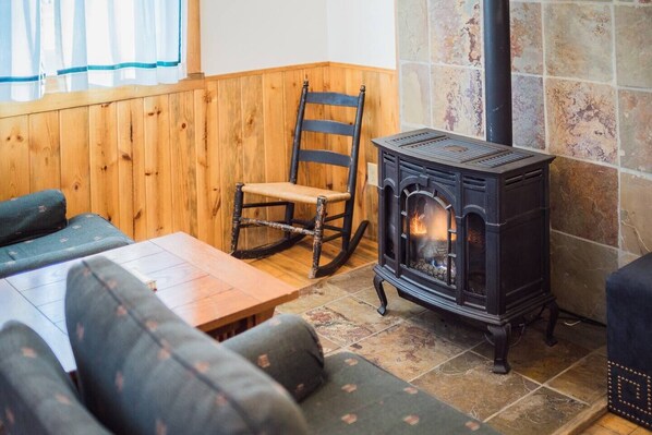 Una habitación acogedora con chimenea de piedra, muebles de madera y un sillón mecedor.