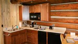 Une cuisine compacte avec des meubles de rangement en bois, un évier, une machine à café et un grille-pain.