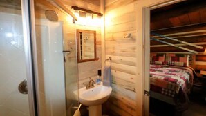 Une petite pièce de cabane en bois comprenant une salle de bain avec un lavabo et un miroir.