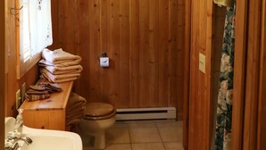 A wooden bathroom with a sink, toilet, and a shower area. - Caron House - A Well-Equipped Square Log Cabin! (Clark)