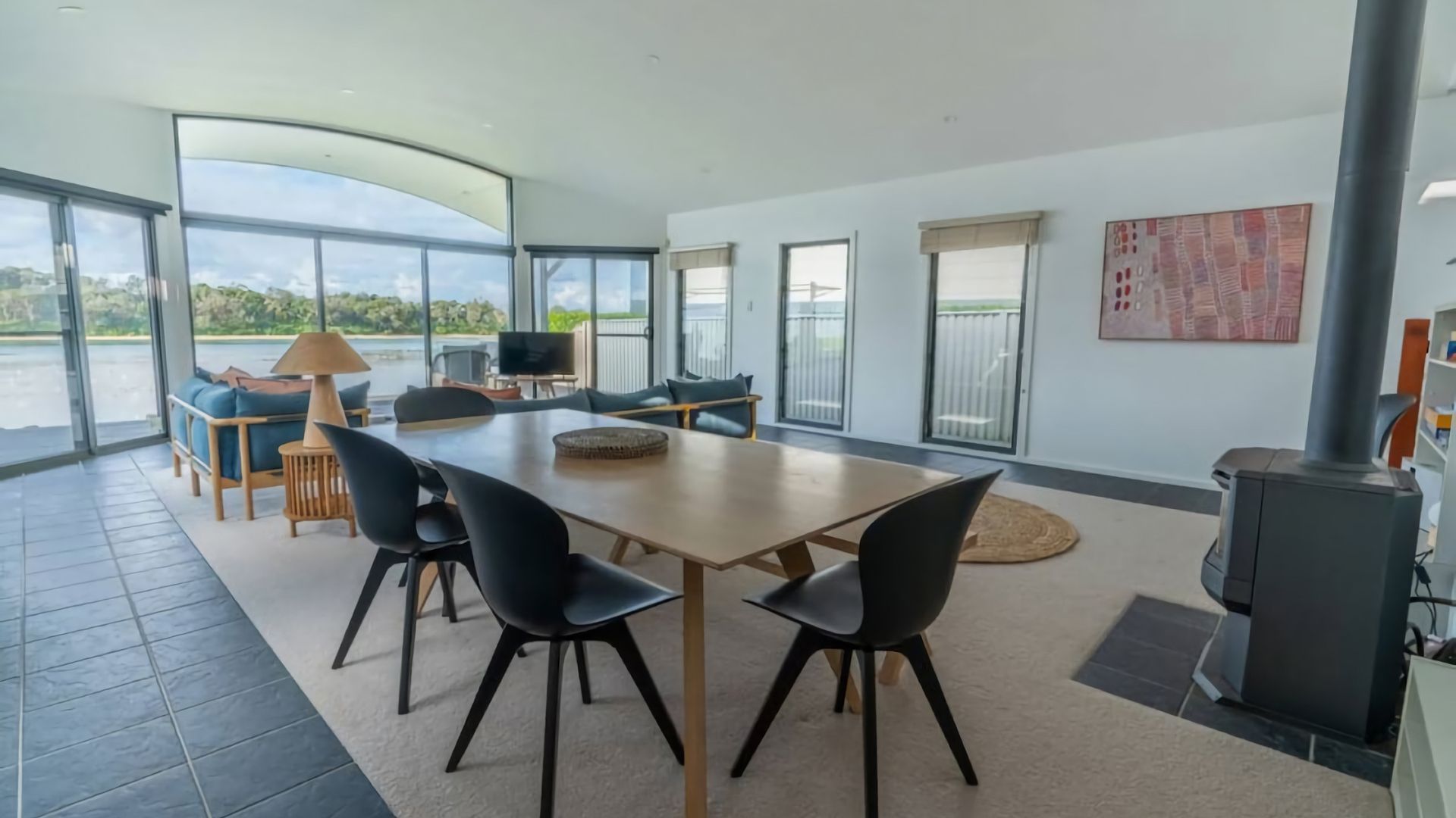 A modern dining area with a large table, chairs, and a view of the outdoors.