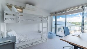Ett rum med en våningssäng, ett skrivbord, en stol och utsikt över naturen.