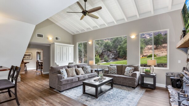 A spacious living room with a high ceiling, large windows, and a fireplace. - The River's Edge - Private Home with River Access, Spa, and Karaoke (Three Rivers)