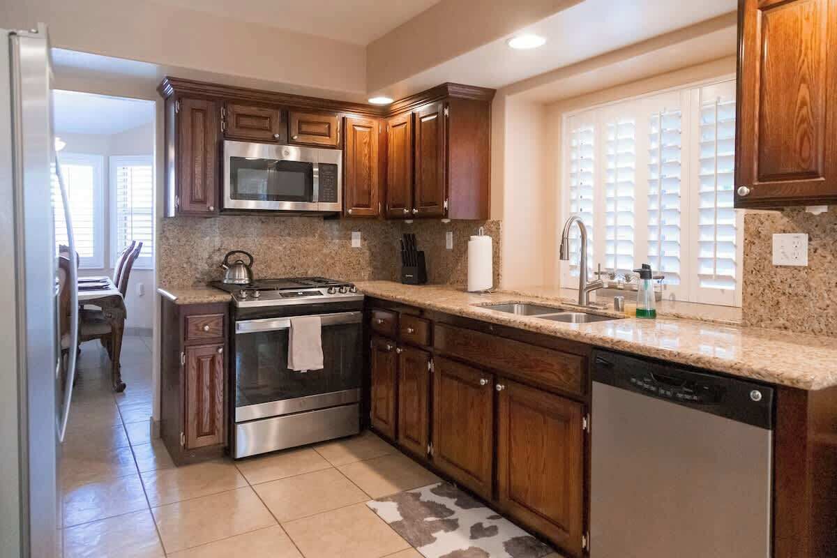 A kitchen with wooden cabinets, stainless steel appliances, a granite countertop, and a dishwasher.