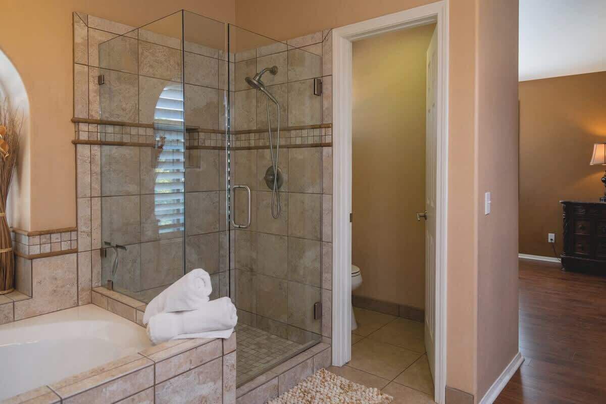 Une salle de bain avec une douche à parois de verre, une baignoire et des toilettes.