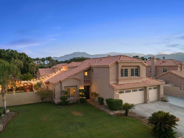 A two-story house with a tiled roof, a garage, and a well-maintained lawn.