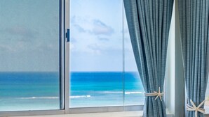 A window with a view of the ocean, curtains tied back, and a starfish decoration.