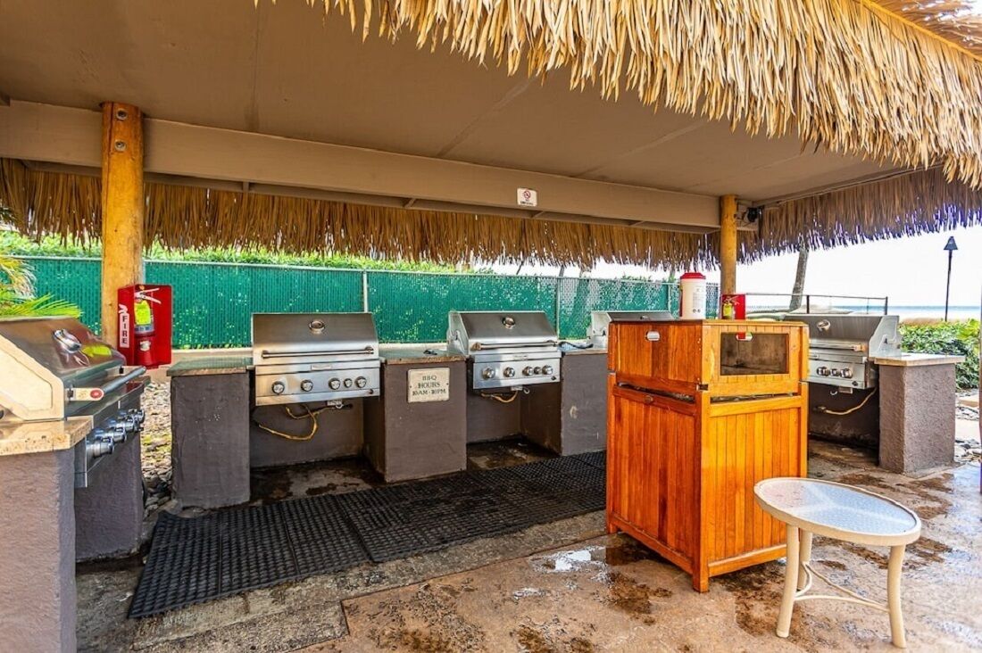 Ein Außenbereich mit Grillstationen und einem Holzkasten, vermutlich zur Lagerung von Lebensmitteln.