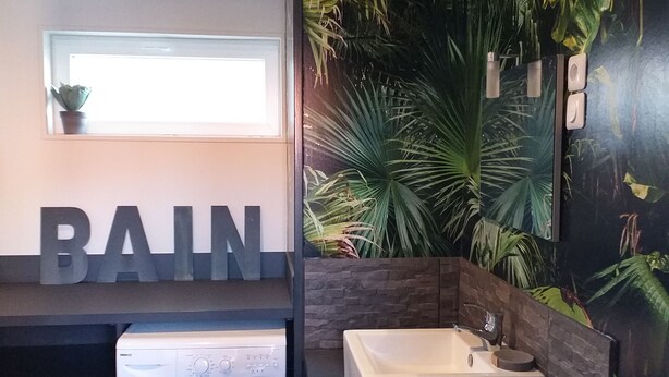 Ein modernes Badezimmer mit integrierter Waschmaschine, einem großen Waschbecken und einem wandmontierten Spiegel.