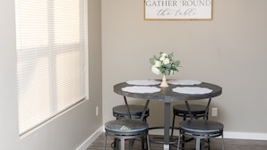 A dining area with a round table, four chairs, and a wall-mounted sign. - Quiet and cozy new townhome minutes from the mall exit. (Barboursville)