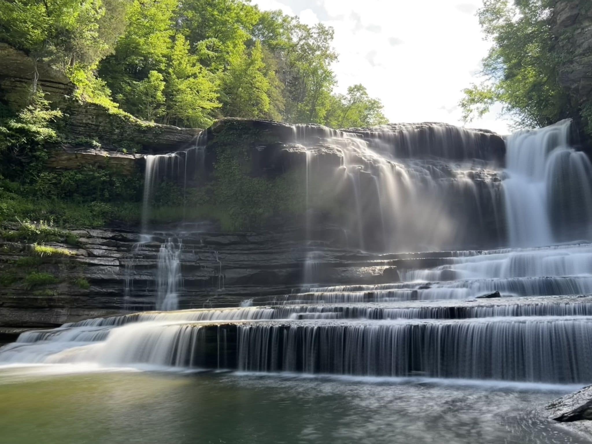 A multi-tiered waterfall surrounded by lush greenery.