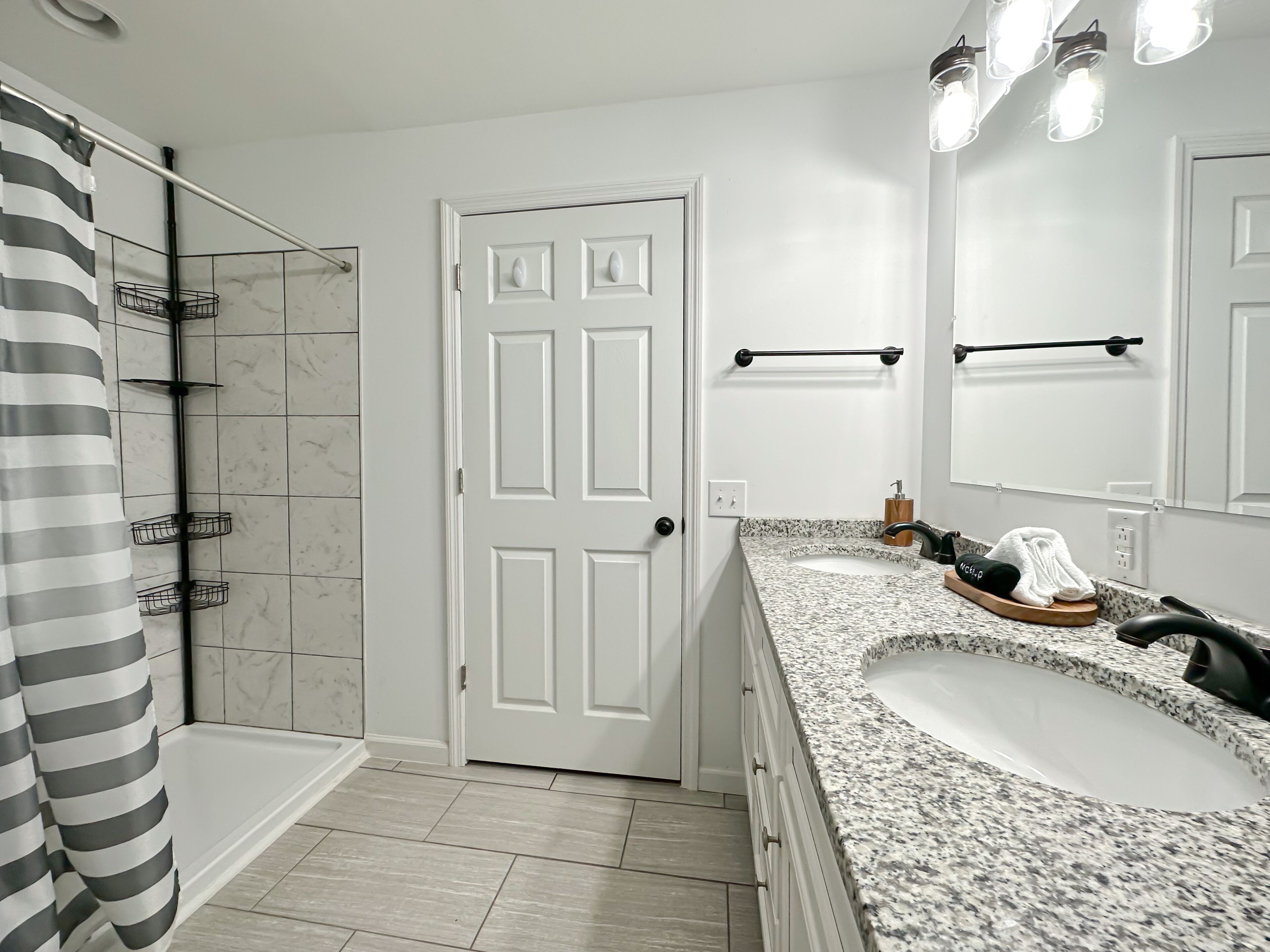 A bathroom with a shower, a sink, and a door.
