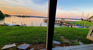 A lakeside view with boats docked, a grassy area, and a pier extending into the water.