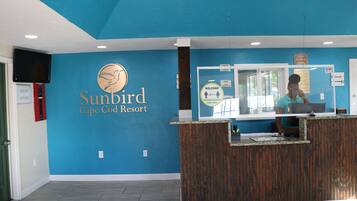 Bancada de recepção no Sunbird Cape Cod Resort, com parede azul e balcão de madeira.