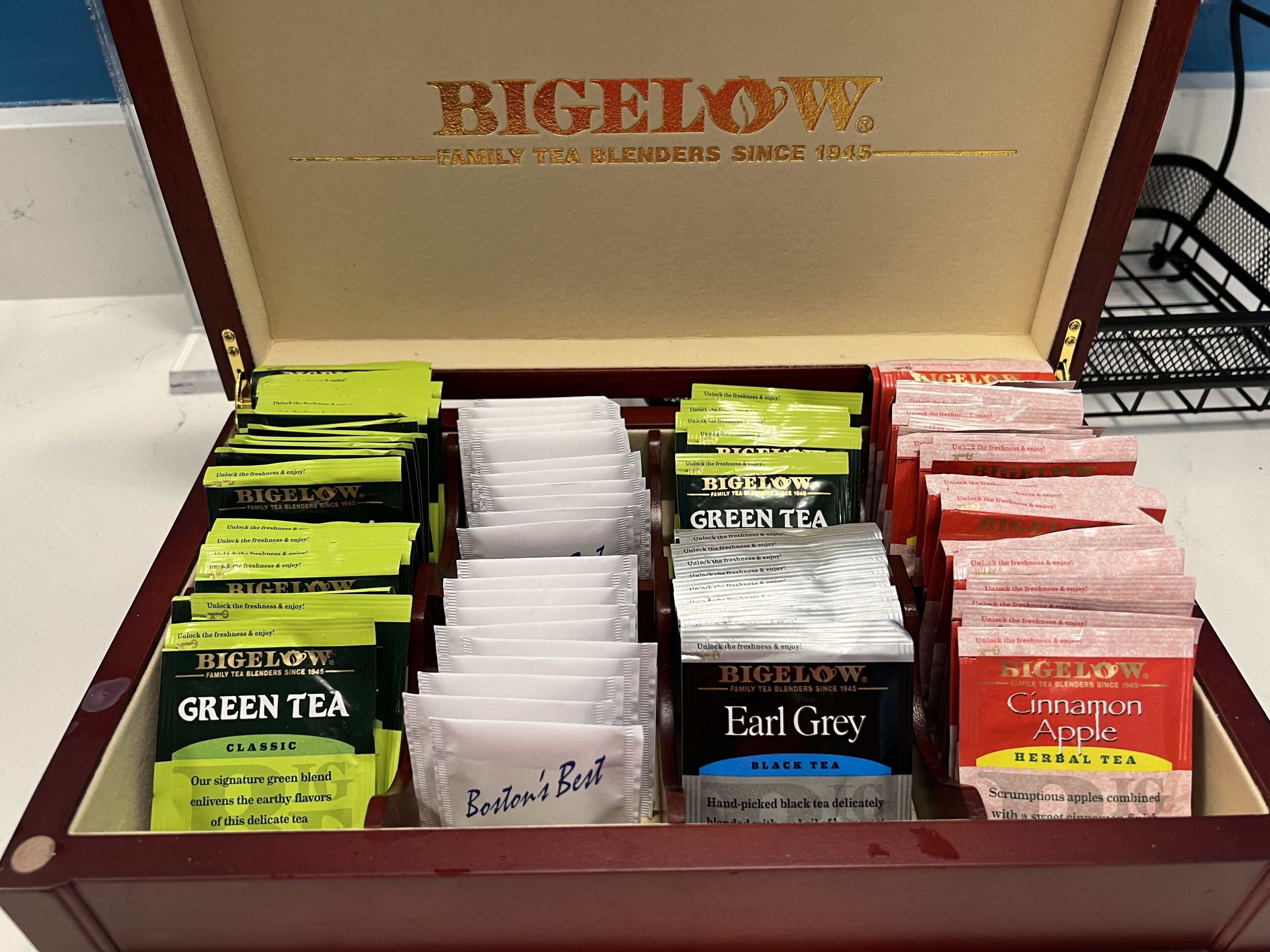 Une boîte de mélanges de thés Bigelow, aux saveurs variées, notamment thé vert, Earl Grey et pomme à la cannelle.