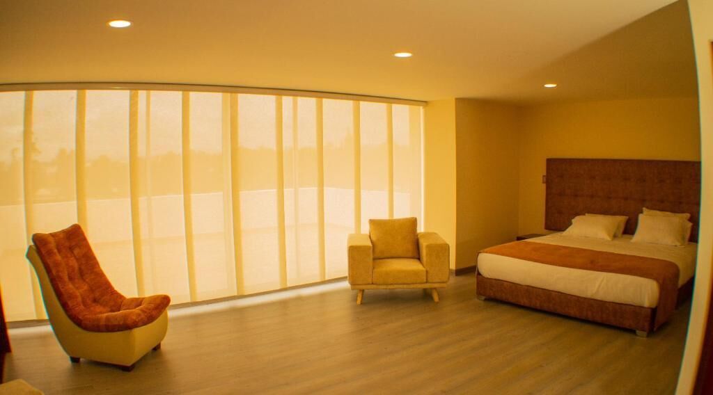 Ein Schlafzimmer mit einem großen Bett, einem Sessel und einem Fenster mit Jalousien.