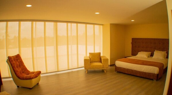 Un dormitorio con una cama grande, una silla y una ventana con persianas.