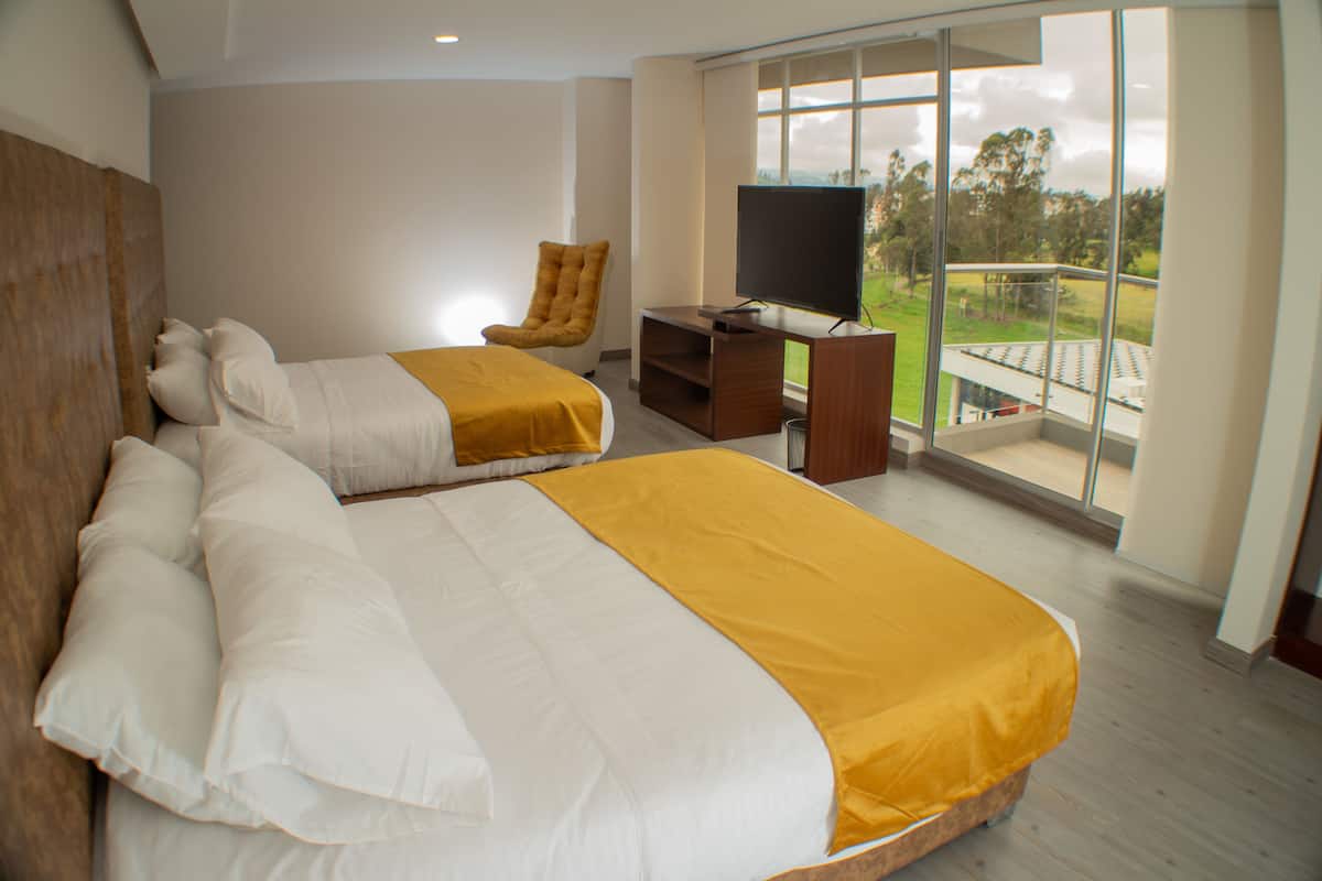 A hotel room with two beds, a TV, and a balcony with a view.
