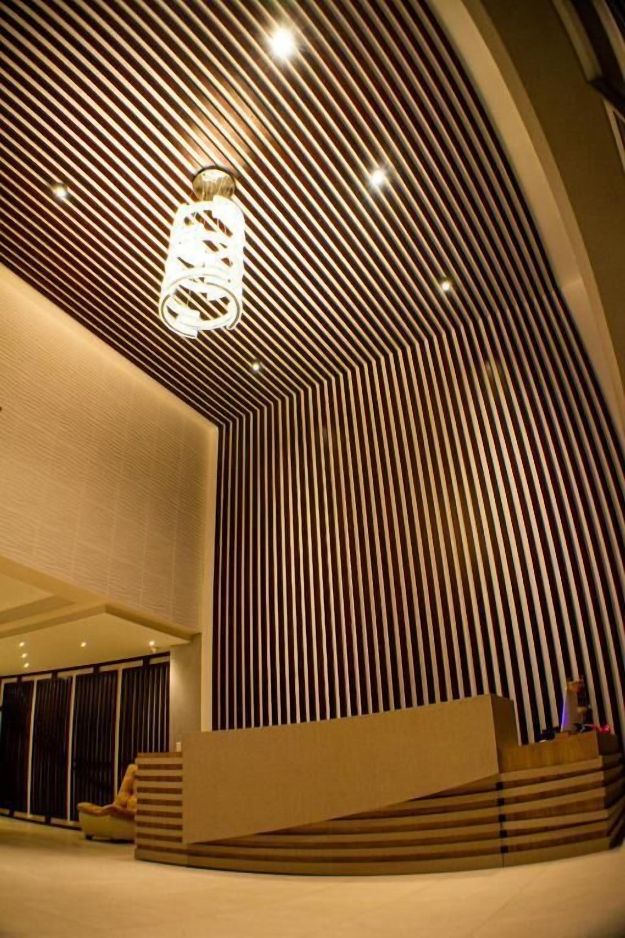 Un interior moderno con techo curvo, una lámpara central y un área de estar con una plataforma baja y escalonada.