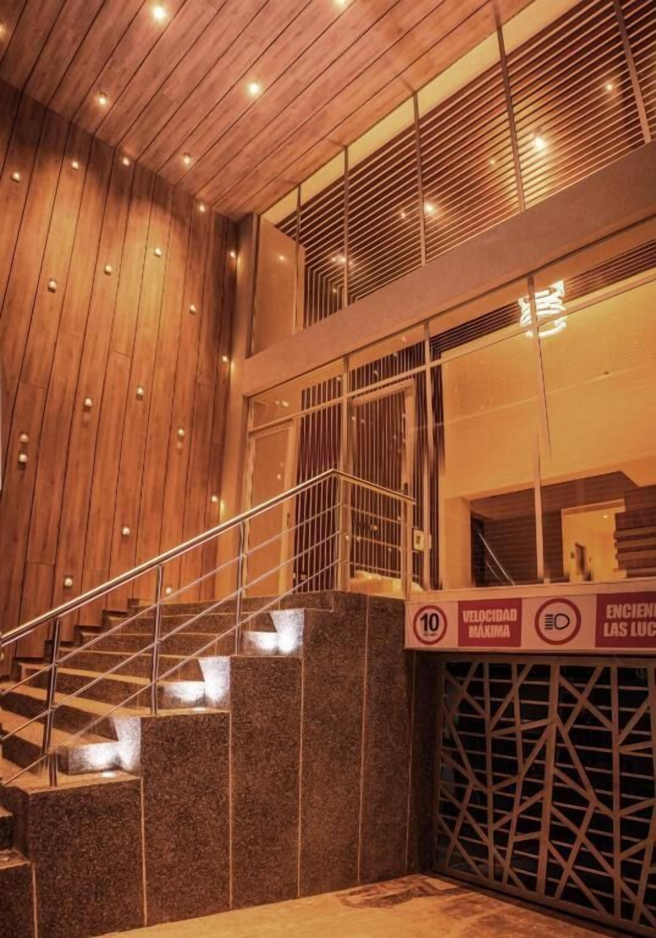 A modern staircase with a wooden finish and glass railings, leading to an upper level.