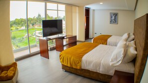 A hotel room with a large window, a bed, a desk with a TV, and a chair. - Harmony Hotel (Ipiales)