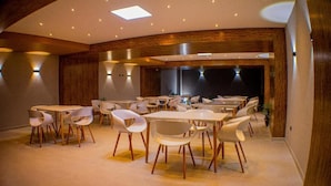 A modern dining area with round tables and white chairs, wooden accents, and recessed lighting. - Harmony Hotel (Ipiales)