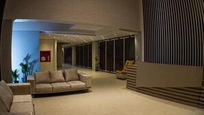 A spacious living area with a sofa, a chair, and a staircase leading to an upper level. - Harmony Hotel (Ipiales)