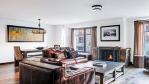 Een moderne woonkamer met lederen meubels, een open haard en grote ramen.