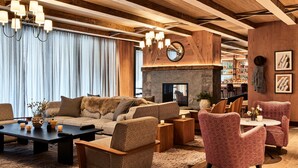 Een gezellige woonkamer met een bank, fauteuils, een salontafel en een open haard.