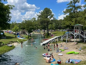En flod där folk ägnar sig åt olika vattenaktiviteter, en lekplats och ett område för picknick.