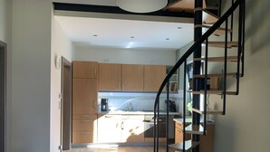 A modern kitchen with wooden cabinets, a built-in oven, and a black spiral staircase leading to an upper level. - Feel-good accommodation, starting point for mountain bike tours and hikes (Höhn)