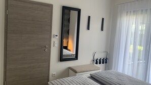 A bedroom with a bed, a bedside table, a mirror, a thermostat, and a window with curtains. - Feel-good accommodation, starting point for mountain bike tours and hikes (Höhn)