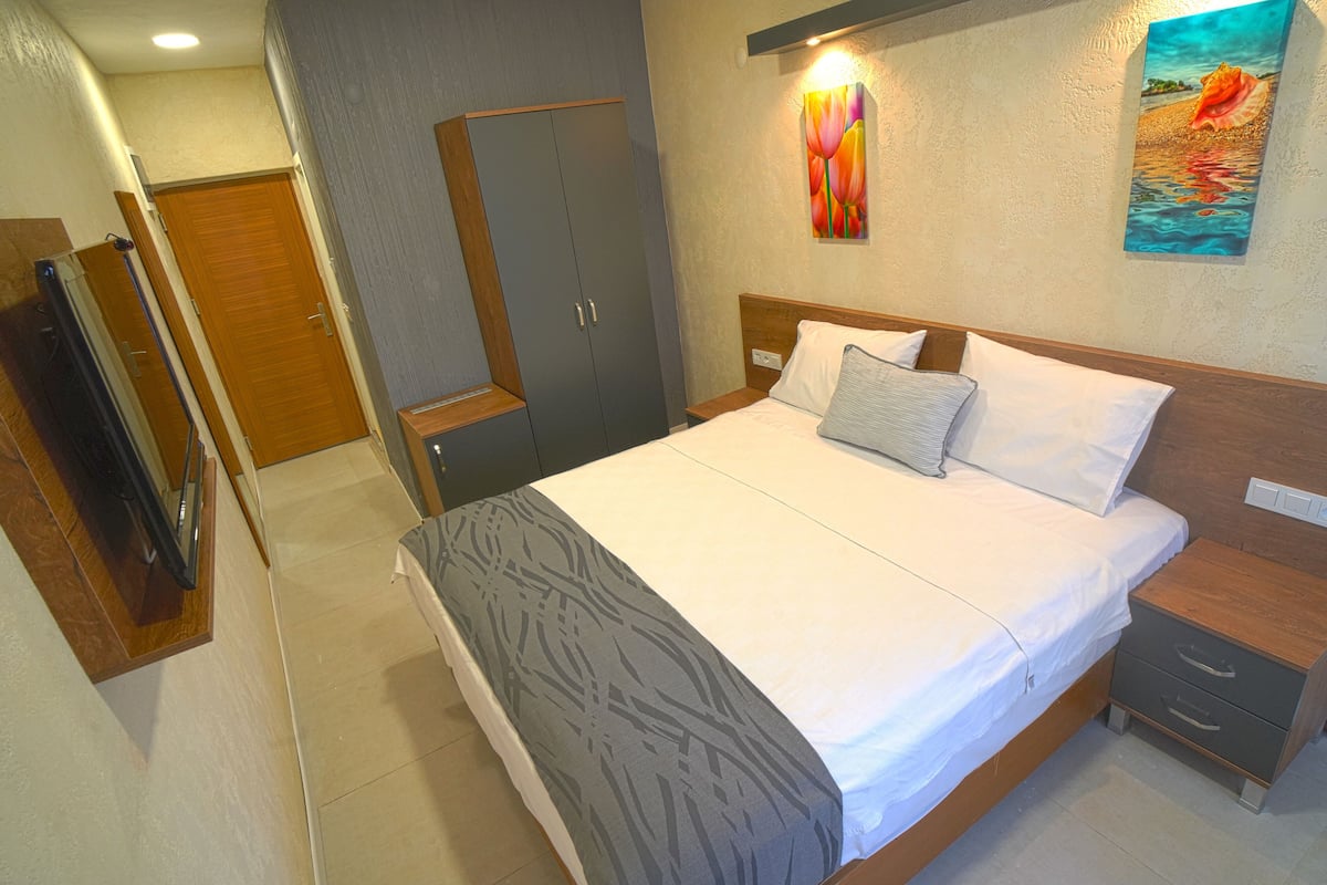 A bedroom with a bed, bedside tables, a wardrobe, and a painting on the wall.