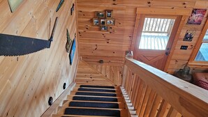 Eine Holztreppe mit Stufen, die mit schwarzem Teppich belegt sind, und einem Holengeländer.